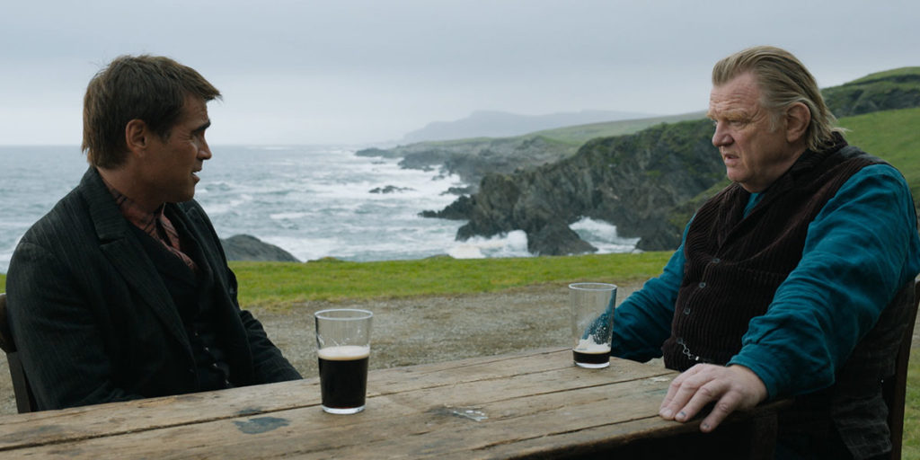 Photo of  Colin Farrell and Brendan Gleeson talking at a table with beer in the film The Banshees Of Inisherin