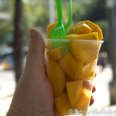 hand holding fresh mangos in a cup