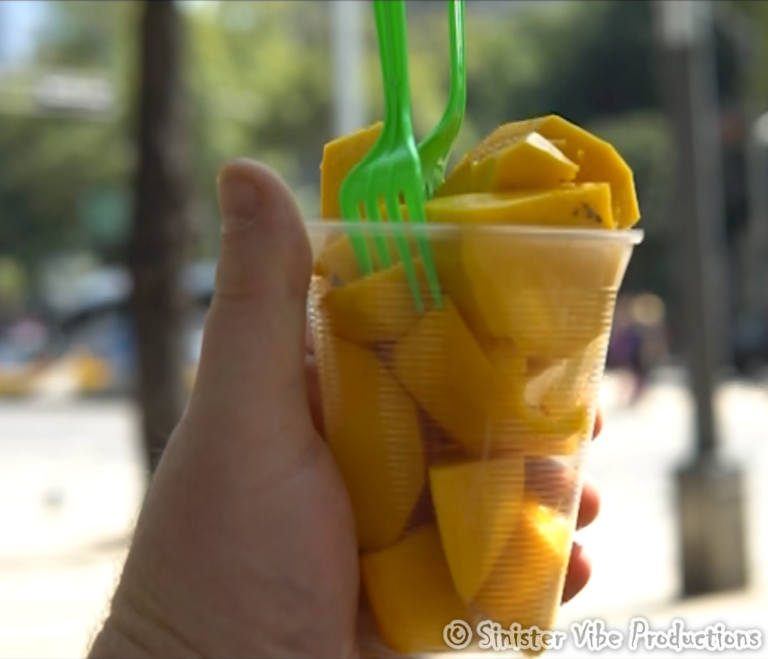 hand holding fresh mangos in a cup