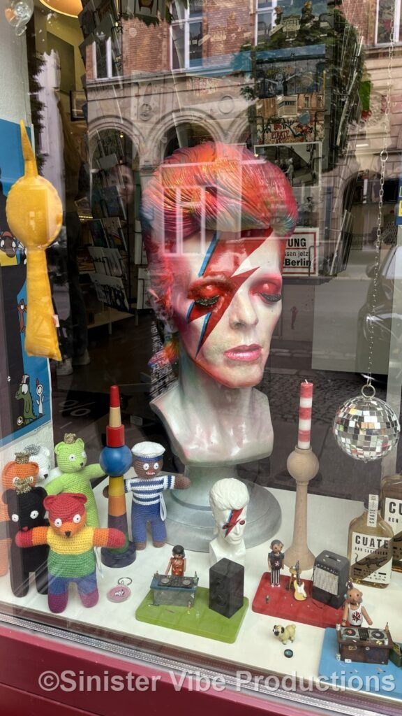 Photo of David Bowie bust in front of a store front.