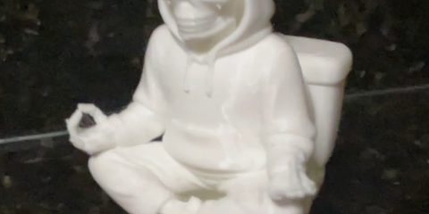 photo of 3d print of a hooded skeleton sitting on a toilet