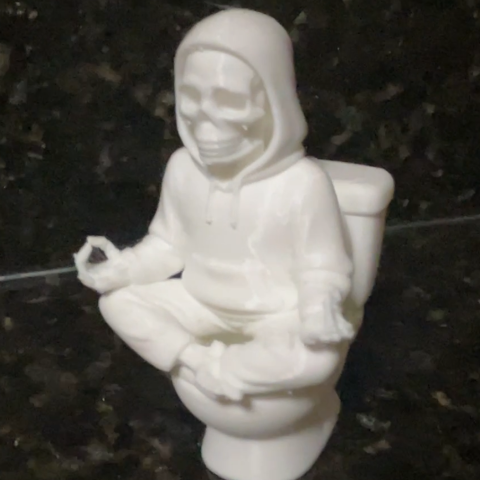 photo of 3d print of a hooded skeleton sitting on a toilet